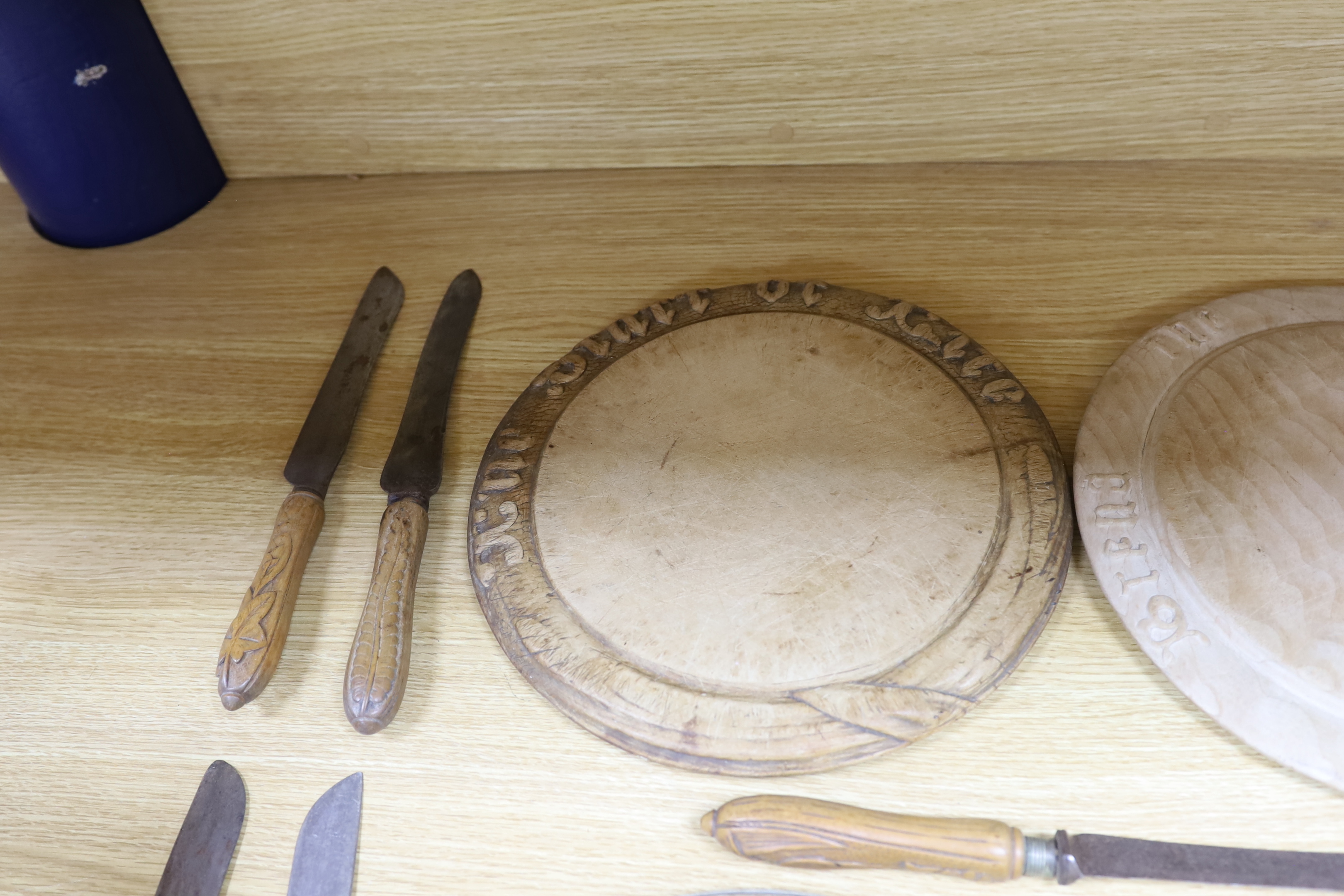 Four carved wood bread boards and a collection of knives with carved handles, boards 28cm in diameter